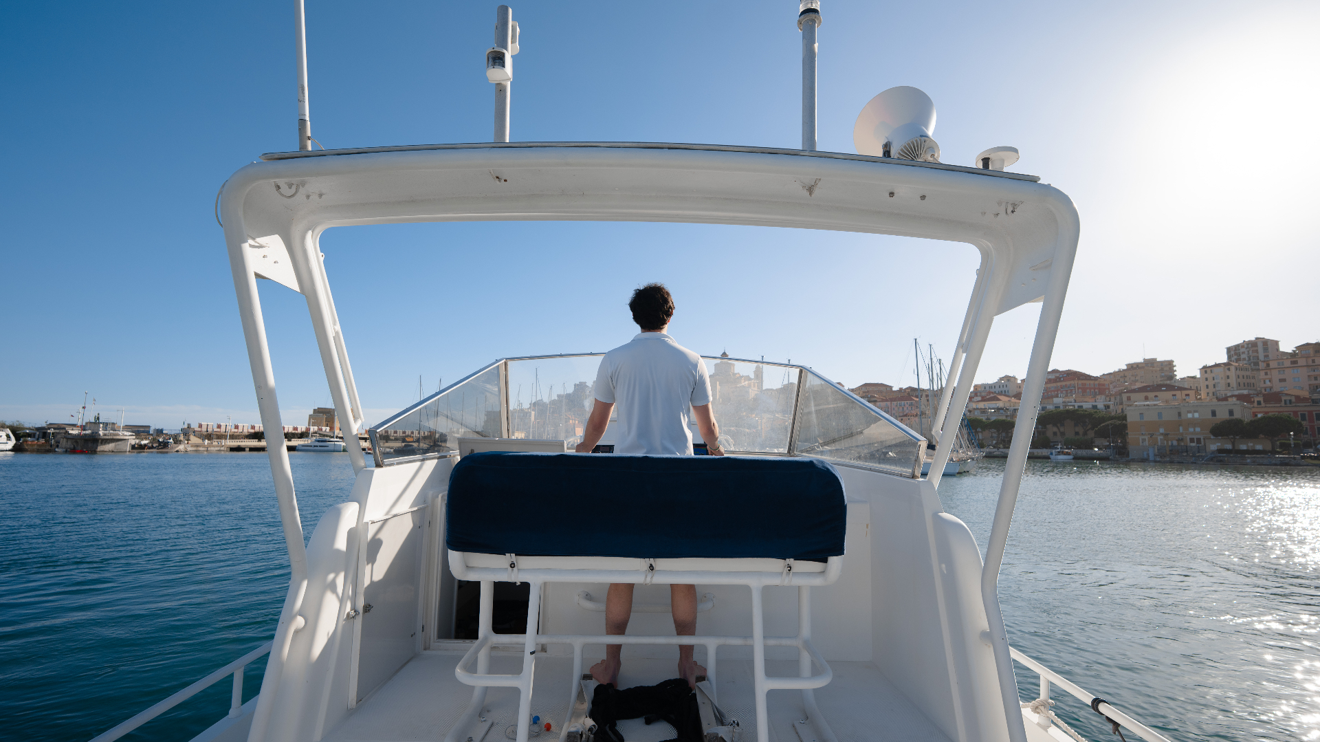 Skipper al timone con vista sul porto di Imperia