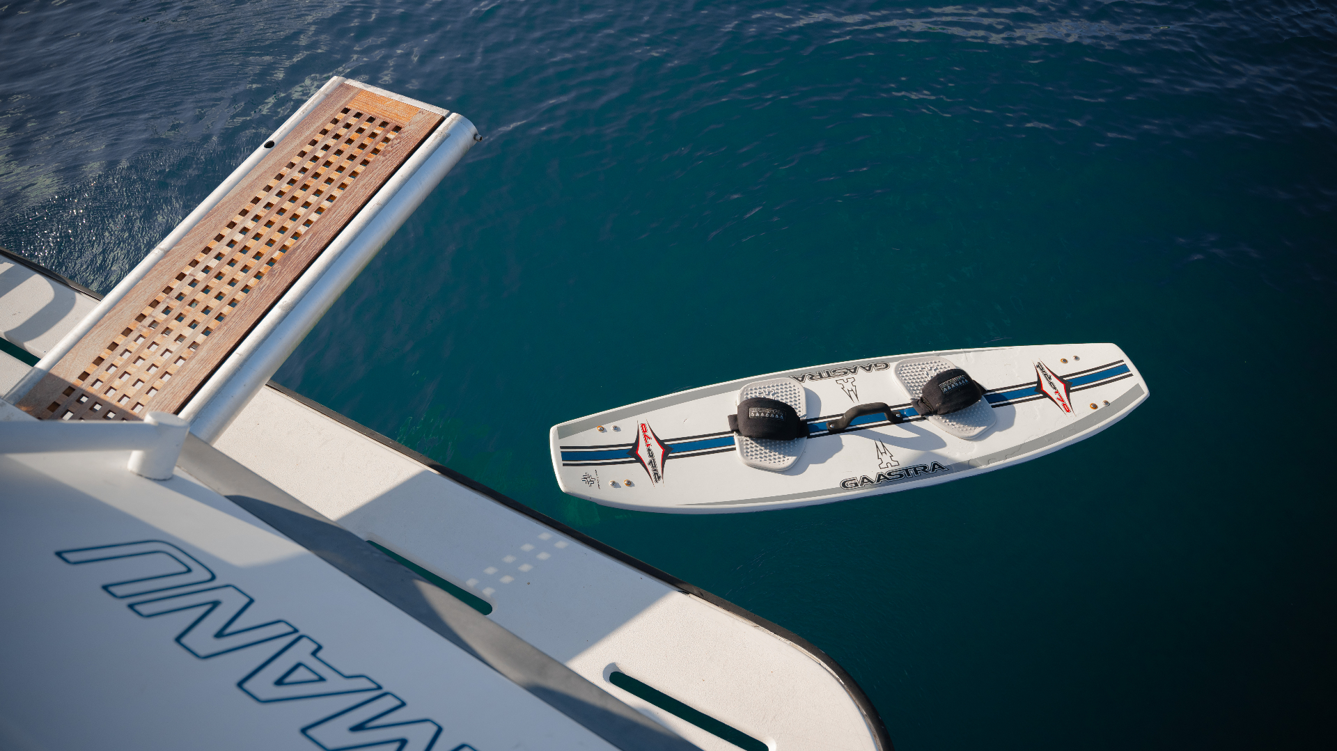 Wakeboard floating on turquoise water by the swim platform